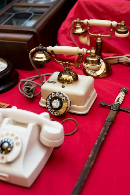 Téléphone ancien à cadran et objets de brocante sur une nappe rouge