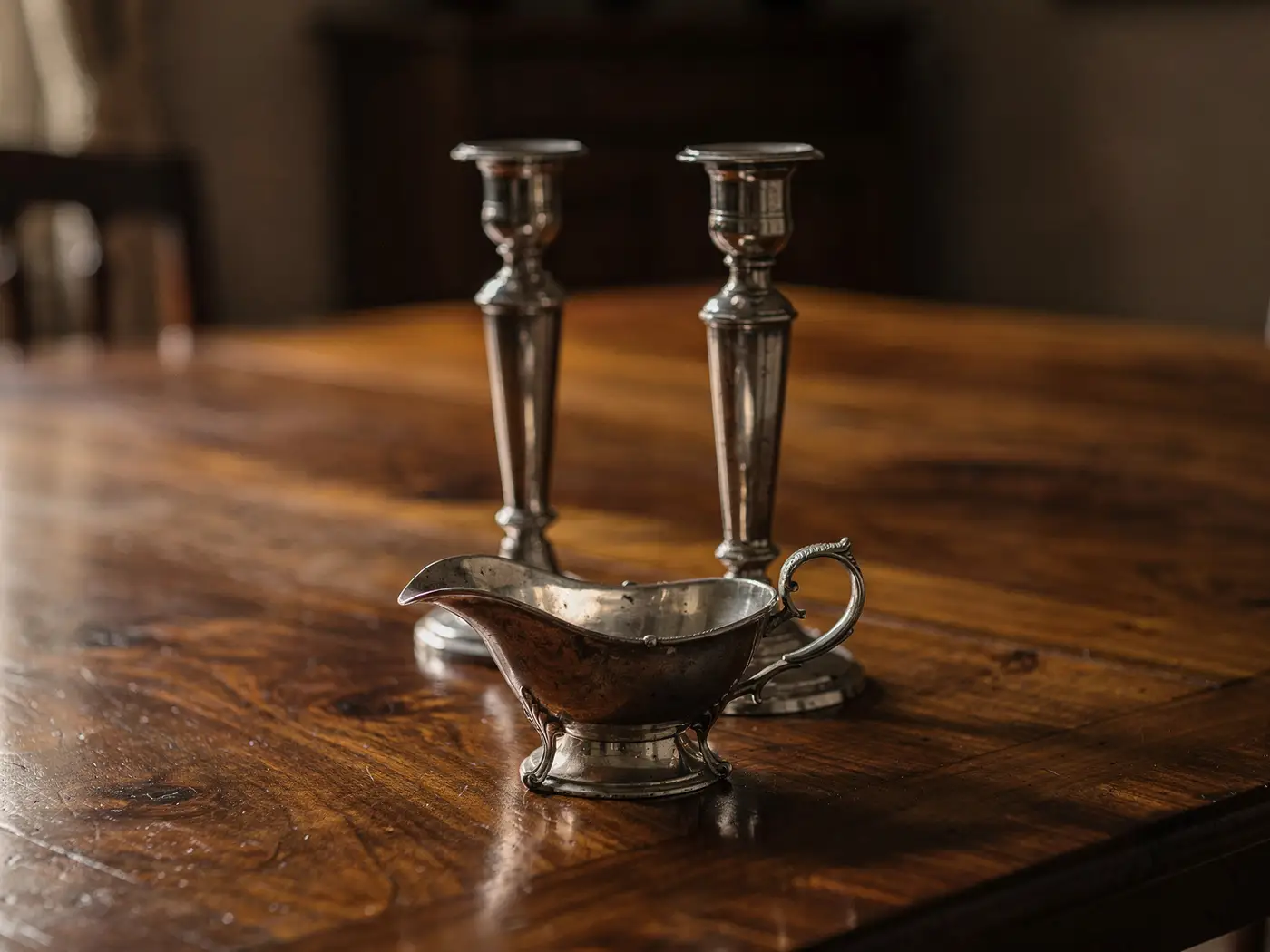 Paire de chandeliers et saucière en argent sur une table en noyer